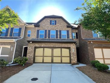 Charming brick townhome with a two-car garage and well-maintained landscaping at 4125 Madison Bridge Dr, Suwanee, GA 30024