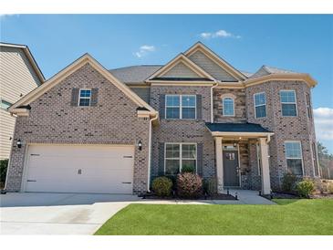 Beautiful brick two-story home with attached two-car garage and manicured lawn on a sunny day at 590 Palm Springs Cir, Fairburn, GA 30213