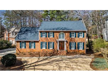 Traditional red brick home with a blue roof, green shutters and manicured landscaping at 4335 Halifax Ne Ter, Roswell, GA 30075