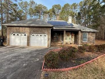 Brick ranch-style home featuring an attached two-car garage, solar panels, and mature landscaping at 5207 W Shore Sw Dr, Conyers, GA 30094