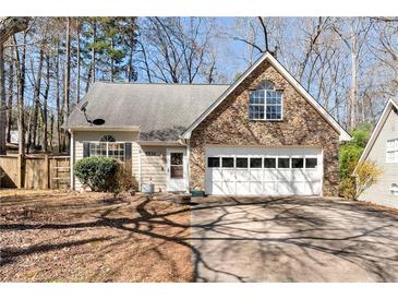 Charming home featuring stone accents, a two-car garage and well-manicured landscaping at 5532 Riverside Dr, Sugar Hill, GA 30518