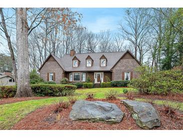 Charming brick home featuring a manicured front yard with mature trees and lush landscaping at 50 Stonington Pl, Marietta, GA 30068