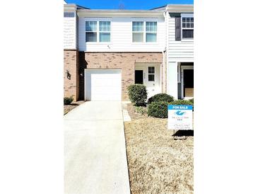 Two-story townhouse featuring a brick facade, attached garage, and neatly landscaped front yard with a for-sale sign at 6408 Kennonbriar Ct, Lithonia, GA 30058