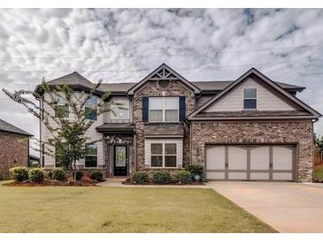 Charming two-story brick home featuring a manicured lawn and attached two car garage at 3419 In Bloom Way, Auburn, GA 30011