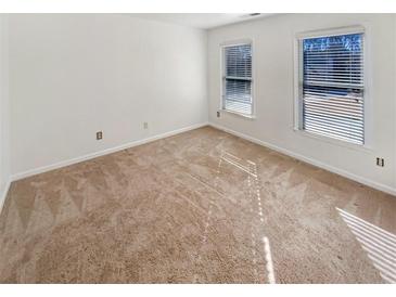 This bedroom has neutral carpet, two windows, and white walls at 5025 Skipping Stone Ct, Cumming, GA 30028