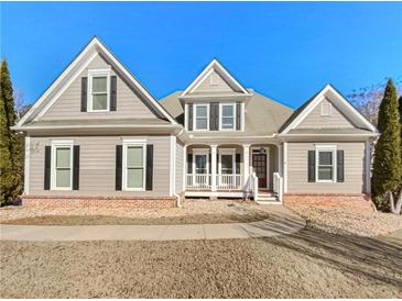 Charming single-Gathering home featuring a well-manicured front yard, classic architecture and welcoming front porch at 5025 Skipping Stone Ct, Cumming, GA 30028