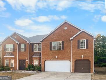 Charming two-story brick home with a well-manicured lawn and an attached two-car garage at 5589 Dendy Trace, Fairburn, GA 30213