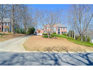 Charming two-story brick home with a well-manicured front yard and a circular driveway at 6450 Oak Valley Dr, Cumming, GA 30040