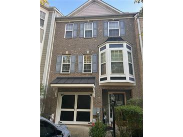 Charming brick townhouse featuring a covered entryway, bay window and a one car garage at 239 Valley Xing, Canton, GA 30114