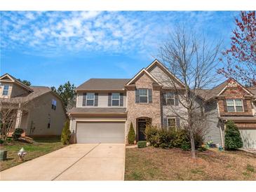 Charming two-story home with a manicured lawn, attached garage, and a combination of stone and siding at 1077 Roanoke Ave, Mcdonough, GA 30253