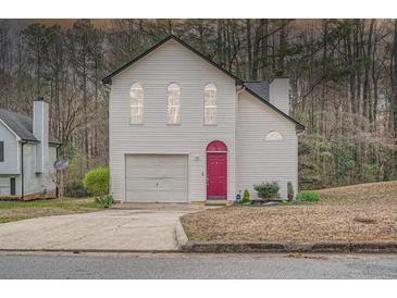 Charming two-story home with white siding, attached garage, and a beautifully colored front door at 2068 Bedford Ct, Lithonia, GA 30058