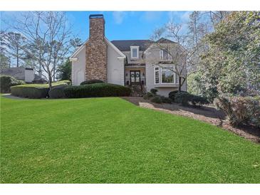 Charming home featuring a stone chimney, landscaped front yard, and well-maintained lawn at 820 Thermopylae Ct, Alpharetta, GA 30005