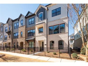Attractive townhome exterior featuring brick and siding, a black metal fence, and manicured landscaping at 710 Hudson Way, Roswell, GA 30076