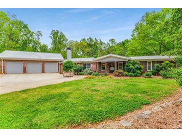 Charming brick ranch with a large front yard, 3-car garage, and metal roof at 3568 Univeter Rd, Canton, GA 30115