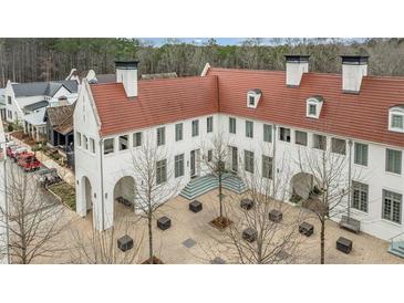 Beautiful European style building with a terracotta roof, white walls, and a courtyard in front at 11279 Serenbe Ln, Chattahoochee Hills, GA 30268