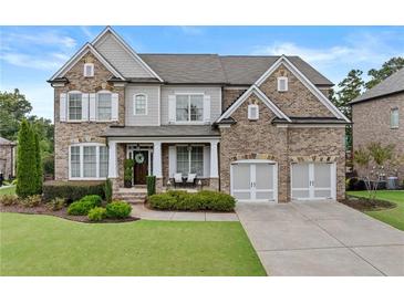Charming brick home with a well-manicured lawn and a welcoming front porch and two-car garage at 3286 Sweetleaf Ln, Buford, GA 30519