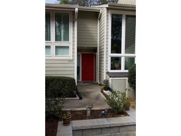 Inviting home entrance featuring a red door, lush landscaping, and abundant natural light through large windows at 1932 Variations Ne Dr, Atlanta, GA 30329