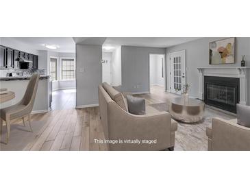 Bright living room featuring a fireplace, wood floors, and open access to the kitchen at 2135 N Forest Trl, Dunwoody, GA 30338