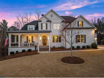 Inviting white brick home with a charming front porch and manicured lawn exudes classic elegance at 6455 Quiet Cove Rd, Cumming, GA 30041