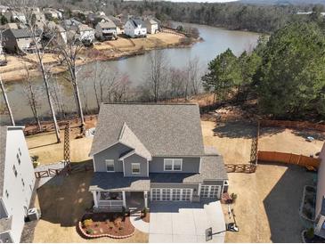 Beautiful two-story gray home with a three-car garage, nestled near a tranquil lake and lush green trees at 6145 Stargazer Way, Cumming, GA 30028