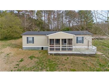 Tan manufactured home with a screened porch and small deck in a natural setting at 718 Old Tennessee Ne Hwy, White, GA 30184