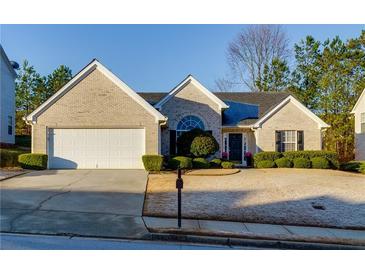 Charming brick home featuring a well-manicured lawn, mature landscaping, and attached two-car garage at 4030 Crescent Walk Ne Ln, Suwanee, GA 30024
