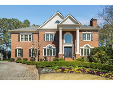 Stately brick home featuring a manicured lawn, mature landscaping, and classic architectural details at 5400 Saint Lyonn Pl, Marietta, GA 30068