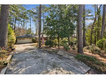 Ranch style home exterior with 2-car garage and long driveway surrounded by mature trees at , Atlanta, GA 30329