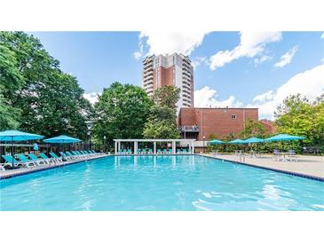 Enjoy the community pool with surrounding lounge chairs and a lush landscape, and a tall building in the background at 375 Ralph Mcgill Ne Blvd # 807, Atlanta, GA 30312