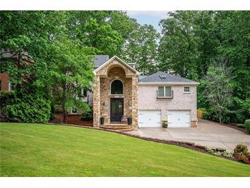 Beautiful brick home with a stone pillar entryway and a well-manicured lawn and mature tree coverage at 3290 Coachmans Ne Way, Roswell, GA 30075