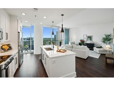 Modern kitchen with white cabinets, stainless steel appliances, and a large island open to the living area at 1080 Peachtree Ne St # 2309, Atlanta, GA 30309