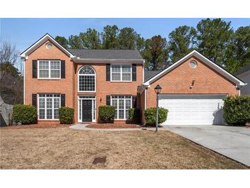 Charming two-story brick home with a well-manicured lawn and a two-car garage at 3876 Elm Trace Ct, Loganville, GA 30052