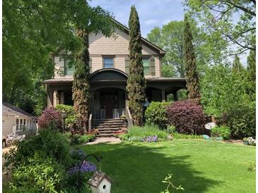 Charming home with a lush front yard, featuring a covered porch, mature landscaping, and a welcoming entrance at 1214 Oglethorpe Ne Ave, Brookhaven, GA 30319
