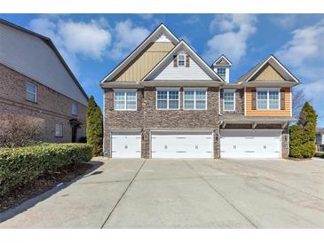 Charming townhome exterior with stone accents, three garages, and a concrete driveway at 805 Pleasant Hill Nw Rd # 343, Lilburn, GA 30047