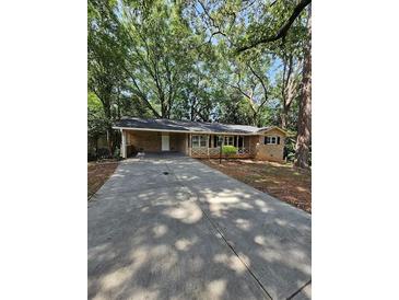 Charming single-story home featuring a long driveway, beautiful mature trees, and a classic brick exterior at 2681 Aquamist Dr, Decatur, GA 30034