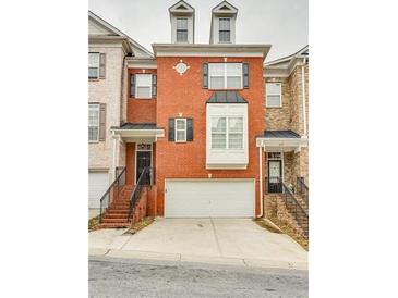 Charming red brick townhouse with a two-car garage and wrought iron stair railing at 215 Aldridge Pl # 9, Smyrna, GA 30082