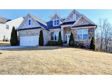 Charming home featuring a stone facade, well-manicured landscaping, and an attached two-car garage at 1431 Torrington Dr, Hoschton, GA 30011