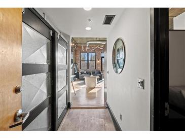 Hallway view into the living room with exposed brick walls and rustic decor, lit by natural light through the windows at 3235 Roswell Ne Rd # 710, Atlanta, GA 30305