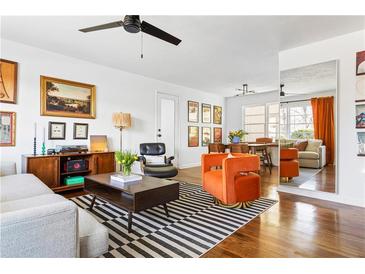 Bright living room boasts hardwood floors, ceiling fan, striped rug, and elegant, comfortable seating at 3720 Cranford Dr, Clarkston, GA 30021