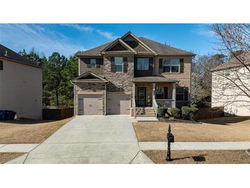 Beautiful two-story home boasts a combination of brick and stone accents, attached two-car garage and a welcoming front porch at 784 Sunset Down Ct, Loganville, GA 30052
