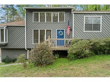 Charming gray home featuring a blue front door with an American flag and neatly landscaped yard at 700 Bayliss Dr, Marietta, GA 30068