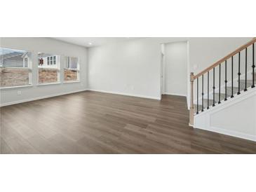 Spacious living room featuring hardwood floors, multiple windows, and staircase at 7758 Sheffield Ter, Fairburn, GA 30213