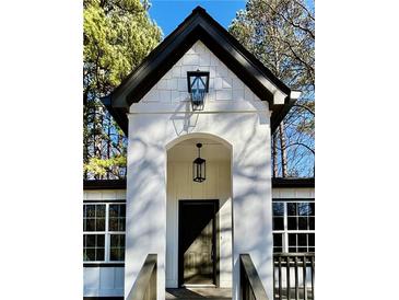 A beautiful home featuring a white facade, arched doorway, and a modern black door, complemented by stylish black hardware and lighting at 3629 Stewart Rd, Atlanta, GA 30340