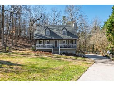 Charming two-story home featuring a cozy front porch, grey siding, and a well-manicured lawn surrounded by mature trees at 504 Hanover Ct, Woodstock, GA 30188