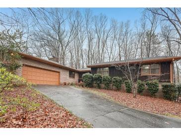 Charming single-story home with brick and dark siding, front yard landscaping and two-car garage at 357 Forest Lake Rd, Lawrenceville, GA 30046
