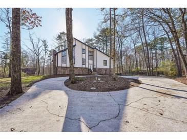 Contemporary home with a circular driveway and stone accents, surrounded by trees at 4013 Brenteresa Ct, Snellville, GA 30039