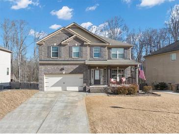 Two-story brick home with a two-car garage, covered porch, and manicured lawn at 5160 Bucknell Trce, Cumming, GA 30028