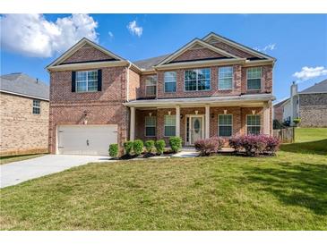 Charming brick two-story home featuring a two-car garage, manicured lawn, and covered front porch at 3772 Sunbridge Dr, Snellville, GA 30039