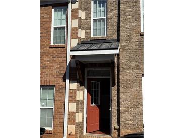 Inviting brick townhouse exterior featuring a red front door with decorative awning and multiple windows at 2372 Johnson Rd, Atlanta, GA 30345