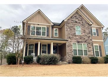 Charming two-story home featuring stone accents, neutral siding, and a welcoming front porch with rocking chairs at 8340 Nolandwood Ln, Villa Rica, GA 30180